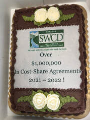 Celebrating over $1 Million Cost-Share Agreements.  Chocolate Cake Picture with Monacan S.W.C.D. logo and text: Over $1 Million In Cost-Share Agreements 2021 - 2022 !  Picture by Sebastian Volcker