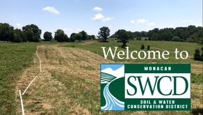 Picture of a partially bush-hogged pasture with water pipe layed out, with Welcome to the Monacan Soil & Water Conservation District surimposed on the picture.  Picture taken at Clover Forest Farm by Sebastian Volcker