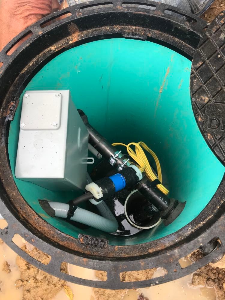 The wide vertical buried pipe where the water from the collects before being pumped to the troughs.
The pipe is aqua colored and jam packed with equipment.  One can see part of the manhole cover.